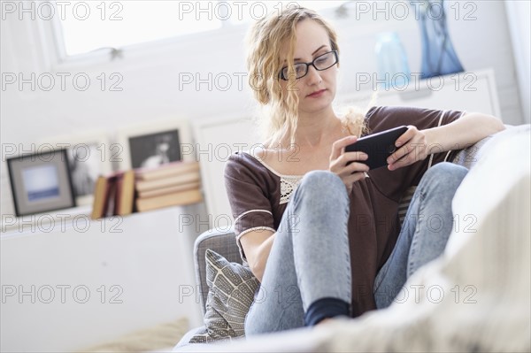 Woman sitting on sofa and using mobile phone.