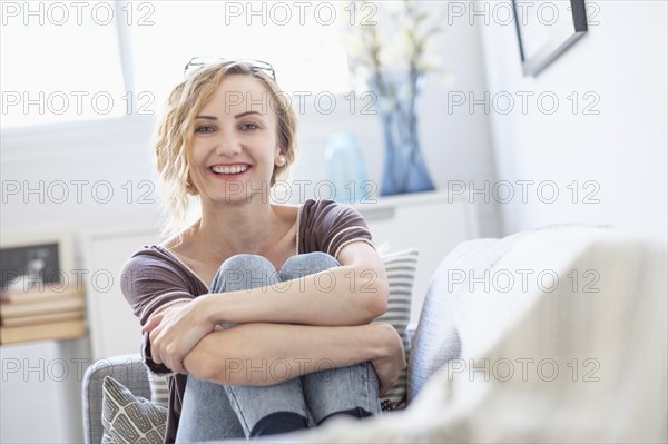 Portrait of woman sitting on sofa in living room.