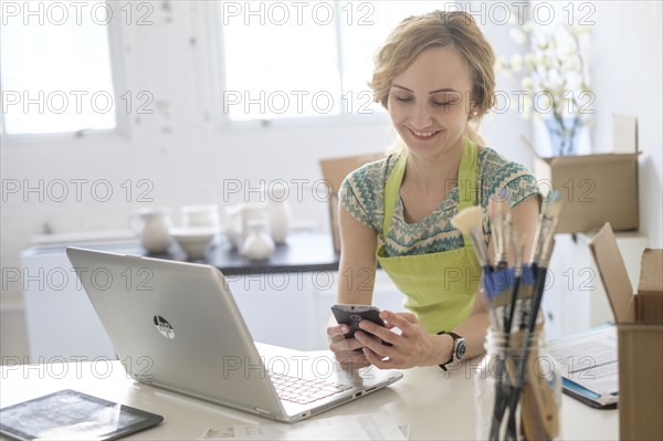 Woman sitting at desk using mobile phone.