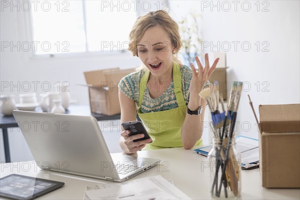 Woman sitting at desk using mobile phone.