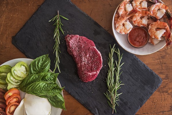 Steak between caprese salad and shrimps