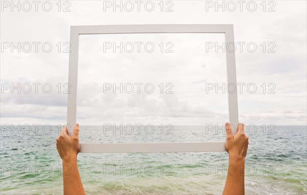 Person holding frame against cloudy sky