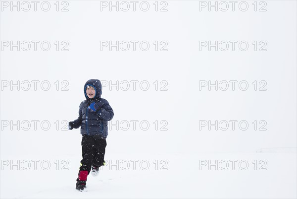 Boy (6-7) running in snow