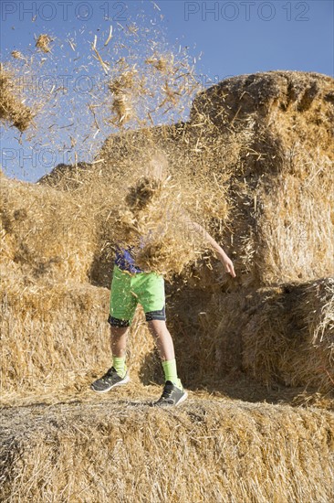 Boy (6-7) playing with hay