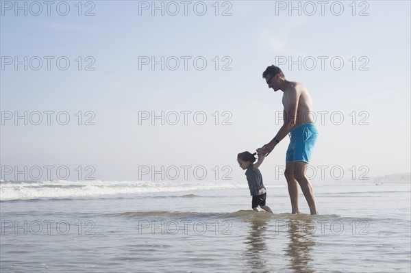 Father with daughter (18-23 months) wading in sea