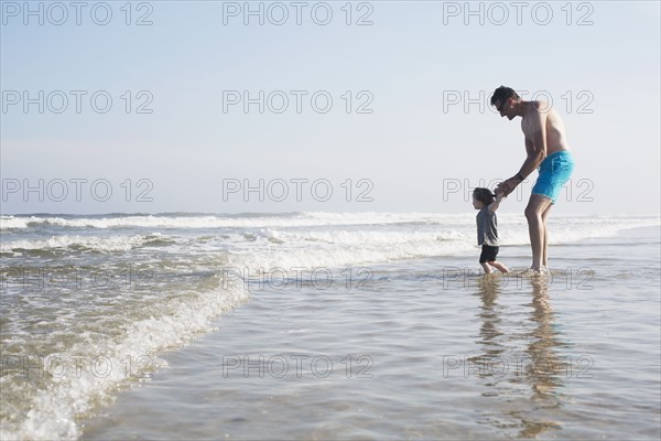 Father with daughter (18-23 months) wading in sea