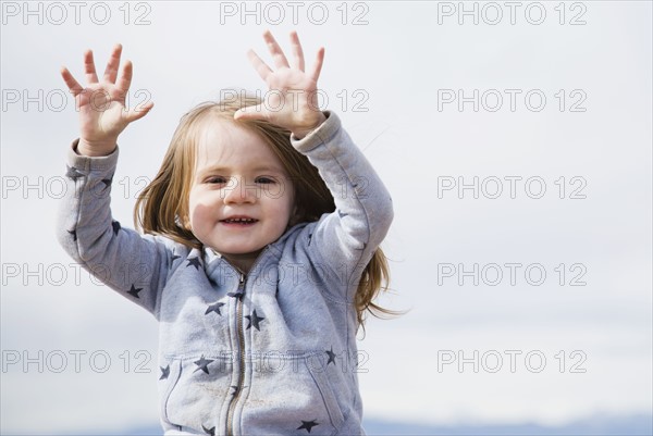 Portrait of baby girl (18-23 months) raising arms