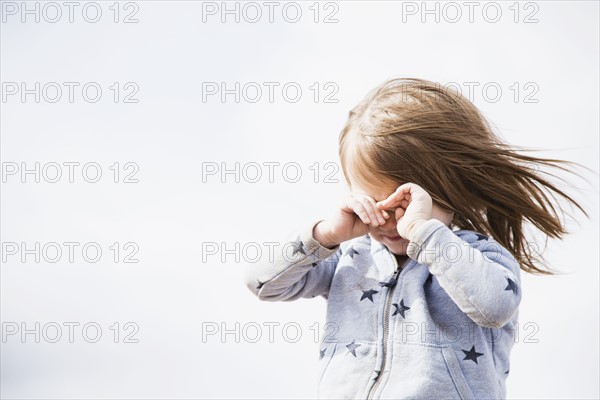 Baby girl (18-23 months) shielding face from wind