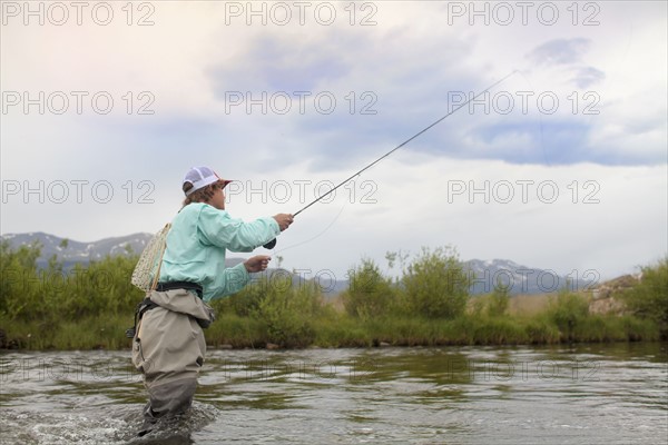 Colorado, Mid adult man wading and fishing in river