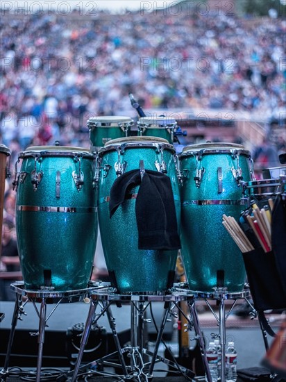 Green drums on stage with audience in background