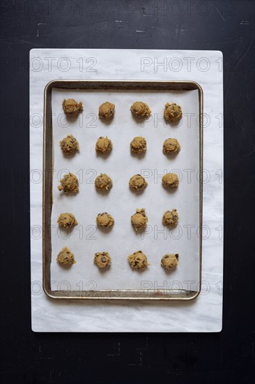 Overhead view of portions of chocolate chip cookie dough on baking sheet