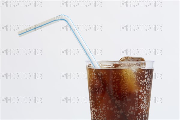 Studio shot of cold drink with ice cubes and plastic straw on white background