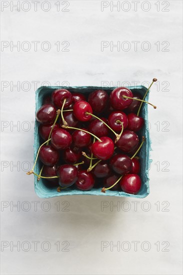 Overhead view of cherries in blue fruit carton