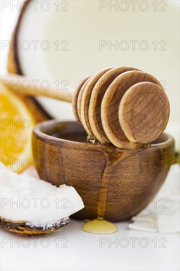 Bowl with honey, honey dipper and coconut