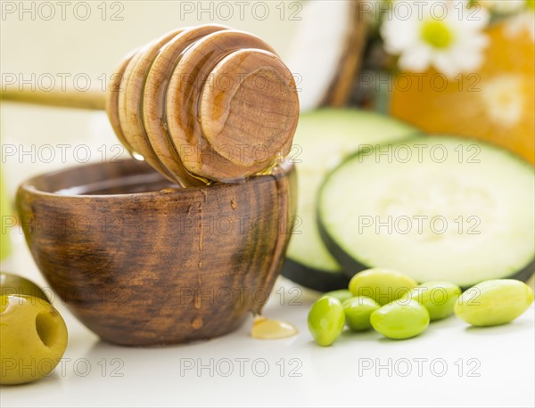 Honey dipper on bowl, olives, peas and slices of cucumber