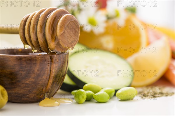 Honey dipper on bowl with honey and fresh vegetables