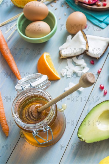 Jar of honey with dipper and fresh ingredients