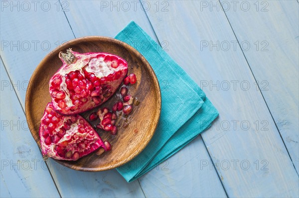 Overhead view of halved pomegranate on wooden plate