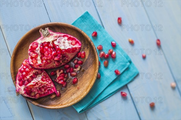Overhead view of halved pomegranate on wooden plate