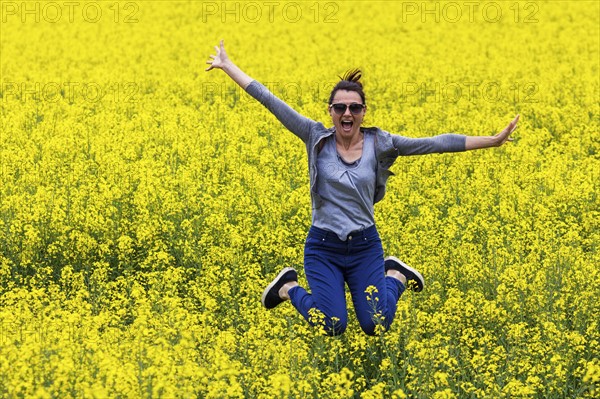 Italy, Tuscany, Woman jumping in canola field