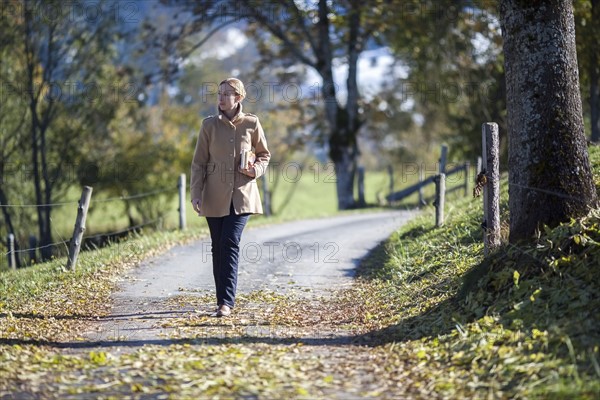 Austria, Salzburger Land, Maria Alm, Mature woman walking on autumn alley