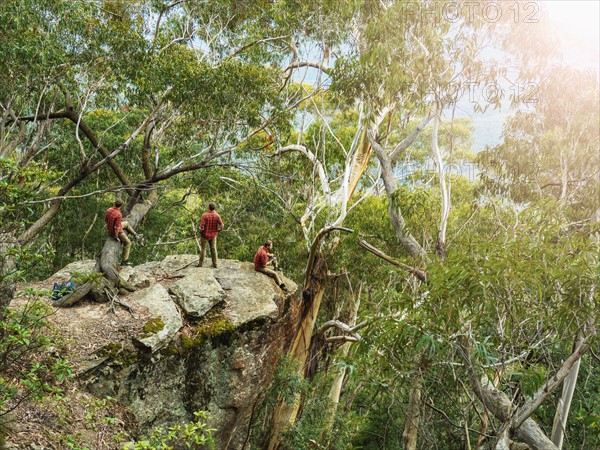 Australia, New South Wales, Katoomba, Three people on cliff in forest in Blue Mountains