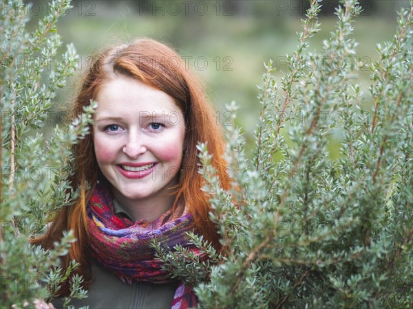 Portrait of smiling redhead in bushes