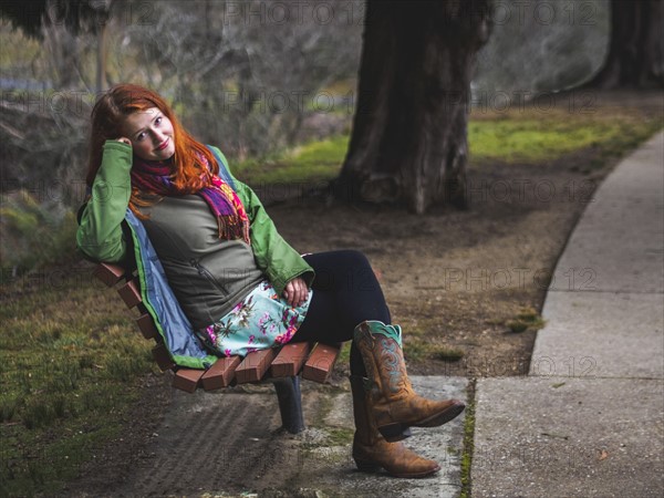 Young woman sitting on bench in park