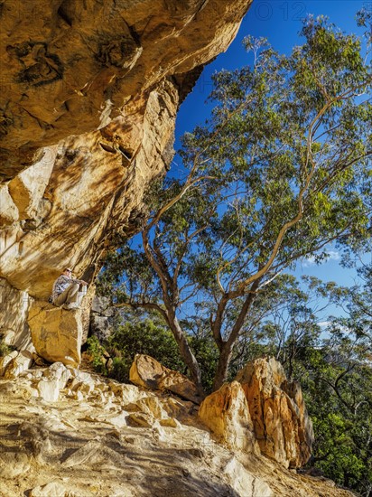 Australia, New South Wales, Blue Mountains, Mature woman resting on rock under cliff in mountain forest