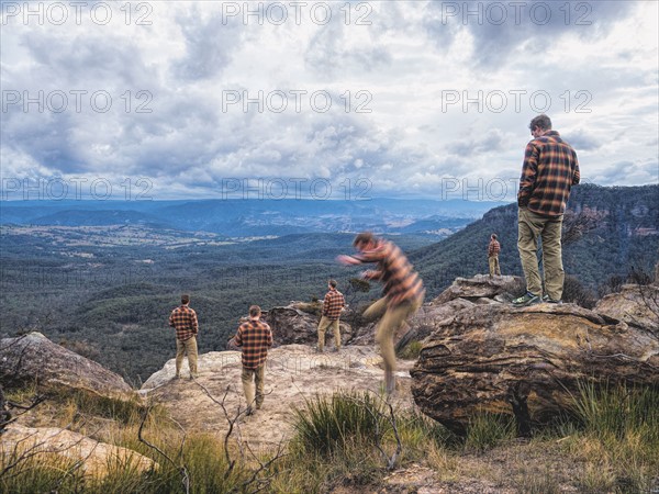 Australia, New South Wales, Blue Mountains, Digitally multiplied photograph of mid-adult man on mountain overlooking valley