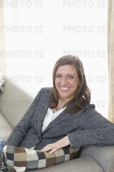 Portrait of smiling mid-adult woman sitting on sofa