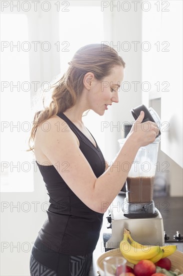 Mid-adult woman preparing smoothie