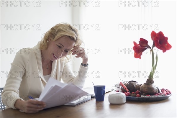 Businesswoman sitting at table at home and reading documents