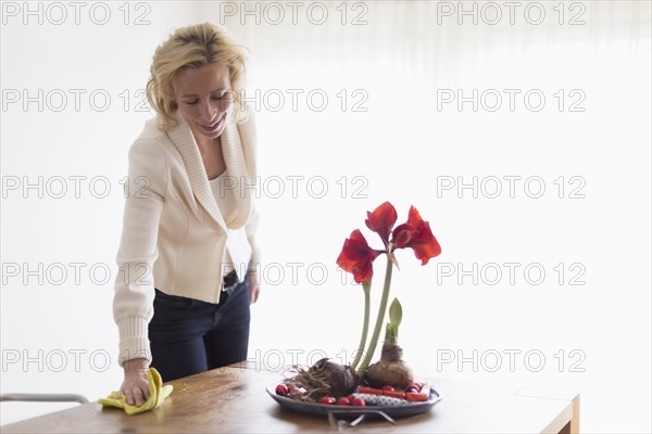 Mature woman cleaning table in living room