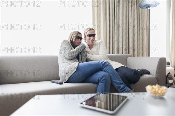 Women in 3d glasses sitting on sofa in living room
