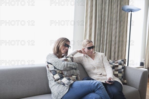 Women in 3d glasses sitting on sofa in living room