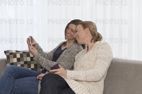 Women sitting on sofa and looking at phone