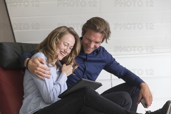 Mid-adult couple looking at tablet and laughing