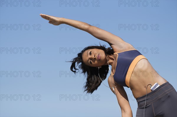 Woman exercising against blue sky.