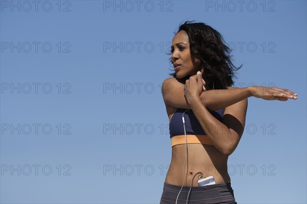 Woman exercising against blue sky.