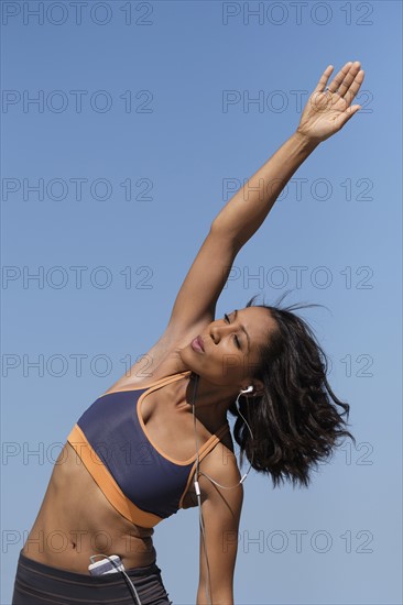 Woman exercising against blue sky.