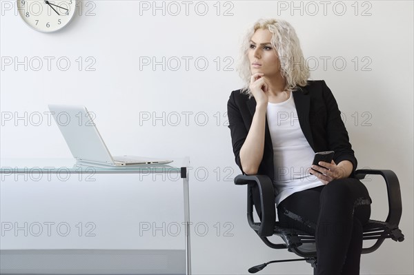 Young businesswoman using phone in office.