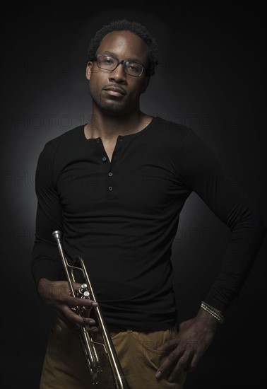 Studio portrait of mid adult man holding trumpet.