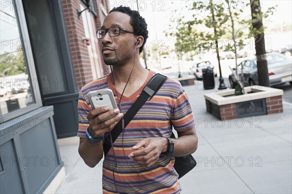 Mid adult man with phone in street.