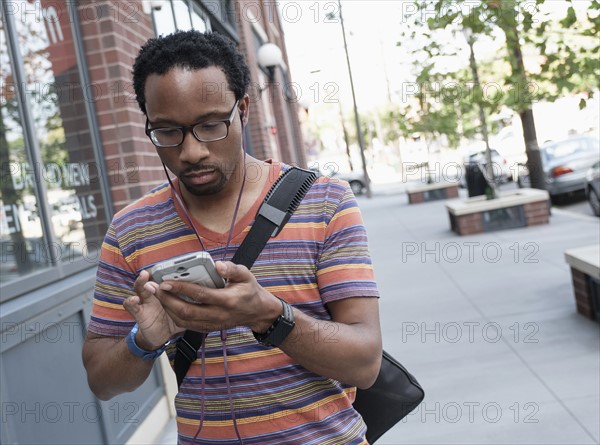 Mid adult man with phone in street.