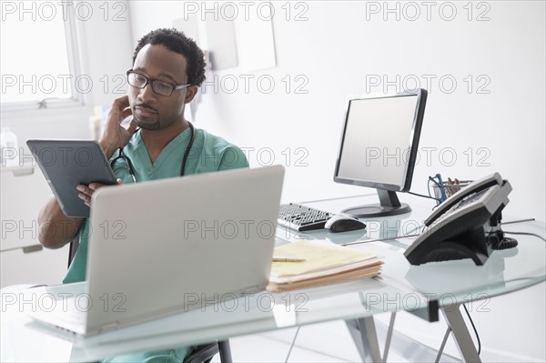 Male doctor working with digital tablet at desk.