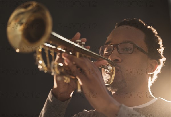 Mid adult man playing trumpet.