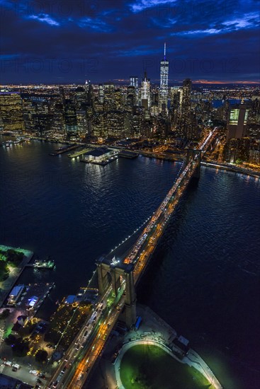 USA, New York, New York City, Manhattan, Aerial view of illuminated skyline with harbor and Brooklyn bridge at night.