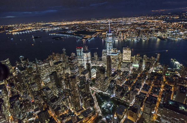 USA, New York, New York City, Manhattan, Aerial view of illuminated skyline with harbor at night.