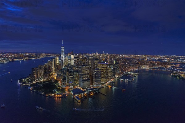 USA, New York, New York City, Manhattan, Aerial view of illuminated skyline with harbor at night.